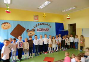 Dzieci z grupy Misiów stoją na tle dekoracji.
