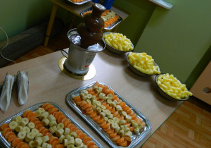 Na stoliku soti fontanna czekoladowa, owoce oraz chrupki przygotowane do skosztowania.