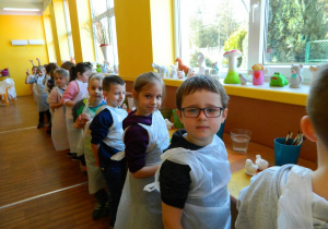 Dzieci ubrane w fartuchy i przygotowane do malowania.