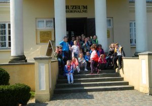 Dzieci siedzą na schodach przed Muzeum Regionalnym w Bełchatowie.