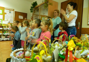 Stojące dzieci z grupy Biedronek przy stole z koszykami wielkanocnymi