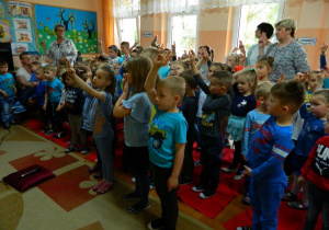 Dzieci z całego przedszkola skłądają przyrzeczenie z podniesionymi dwoma palcami.