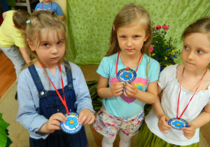 Trzy dziewczynki prezentują medale od wesołej niezapominajki.