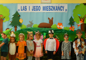 Dzieci z grupy Misiów w przebraniach zwierząt stoją na tle dekoracji.
