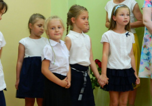 Dwie dziewczynki podczas śpiewu trzymają się za ręce.