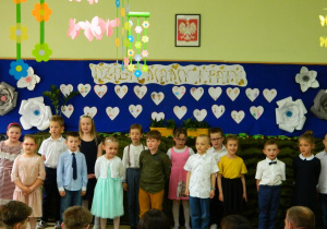 Dzieci z grupy Motylków stoją na tle dekoracji w serca.