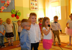 Troje dzieci z grupy Krasnali mówi wiersz do mikrofonu.