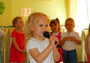 Dziewczynka mówi wiersz o rodzicach do mikrofonu.