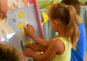 Dwoje dzieci układa puzzle z żółtą kaczuszką.