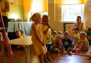 Dwoje dzieci z grupy Krasanali śpiewa piosenkę.