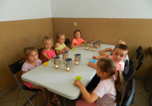 Dziewczynki i chłopcy siedzą przy stole z foremkami do mydełek.