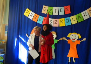 Nauczycielka w przebraniu Krsnala Hałabały wraz z dyrektorem witają dzieci.