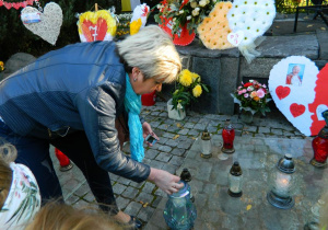 Pani Grażynka zapala znicz pod pomnikiem Jana Pawła II