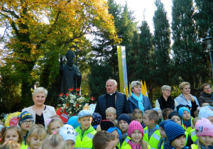 Zdjęcie grupwe z dyrektorem i proboszczem pod pomnikiem Jana Pawła II