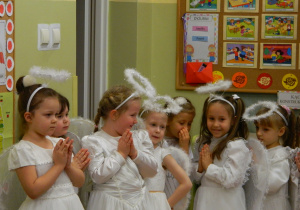 Dziewczynki stoją w przebraniach aniołków w oczekiwaniu na występ