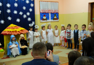 Aniołki i dzieci z trókątami śpiewają pastorałkę.