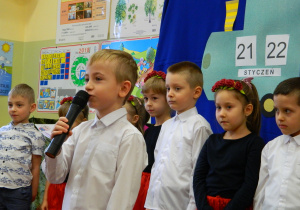 Chłopiec recytuje wiersz do mikrofonu.