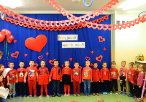 Dzieci ubrane na czerwono śpiewaja piosenkę.