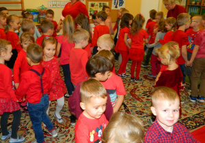 Dzieci wspólnie tańczą na dywanie.