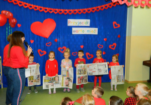 Dzieci trzymają w ręku gazety potzrebne do konkursu.