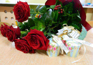 Czerwone róże w bukiecie z małymi prezencikami.