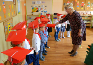 Dzieci są uroczyście pasowane czerwonym ołówkiem przez panią dyrektor