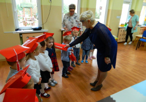 Pani dyrektor dotyka ramienia dzieci czerwonym dużym ołówkiem