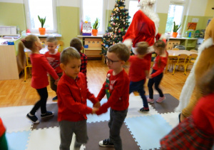 Chłopcy i dziewczynki tańczą w parach z Mikołajem