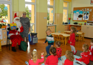 Mikołaj razem z panią dyrektor pokazują dzieciom prezenty