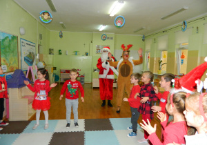 Wspólny taniec dzieci z Mikołajem i reniferem