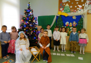 Dziewczynki i chłopcy śpiewają kolędę dla świętej rodziny
