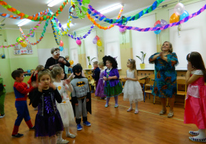 Dzieci z grupy Motylków w przebraniach tańcząwraz ze swoimi wychowawcami