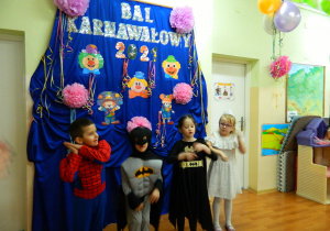Chłopcy i dziewczęta w przebranaich batmana, spidermana i damy tańczą na tle dekoracji