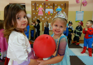 Dziewczynki tańczą trzymając czerwonego balona pomiedzy brzuszkami