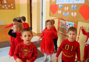 Chłopcy i dziewczęta tańczą z czerwonymi wstążkami