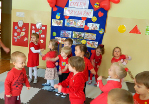 Dzieci w czerwonych bluzeczkach tańcza do muzyki
