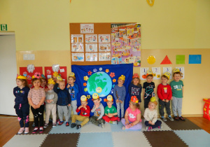 Dzieci stoja na tle dekoracji z Ziemią w opaskach na głowach