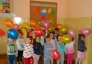 Dzieci z grupy Wiewiórek stoją na tle tablicy z napisem Dzień Dziecka trzymając w ręku balony