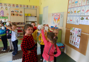 Dzieci z grupy Misiów tańczą trzymając w rękach białe kwiatki