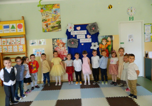 Dzieci z grupy Biedronek stoją w półkolu na tle dekoracji