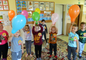 Dziewczynki i chłopcy z grupy Misiów trzymają wysoko podniesione balony