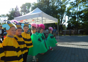 Dzieci w przebraniach kwiatów i pszczół oczekują na występ